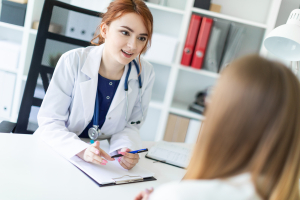 female doctor taking notes while talking with a patient