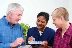caregiver giving elderly couple medicine