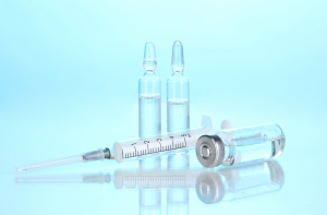 syringe and medical ampoules on blue background